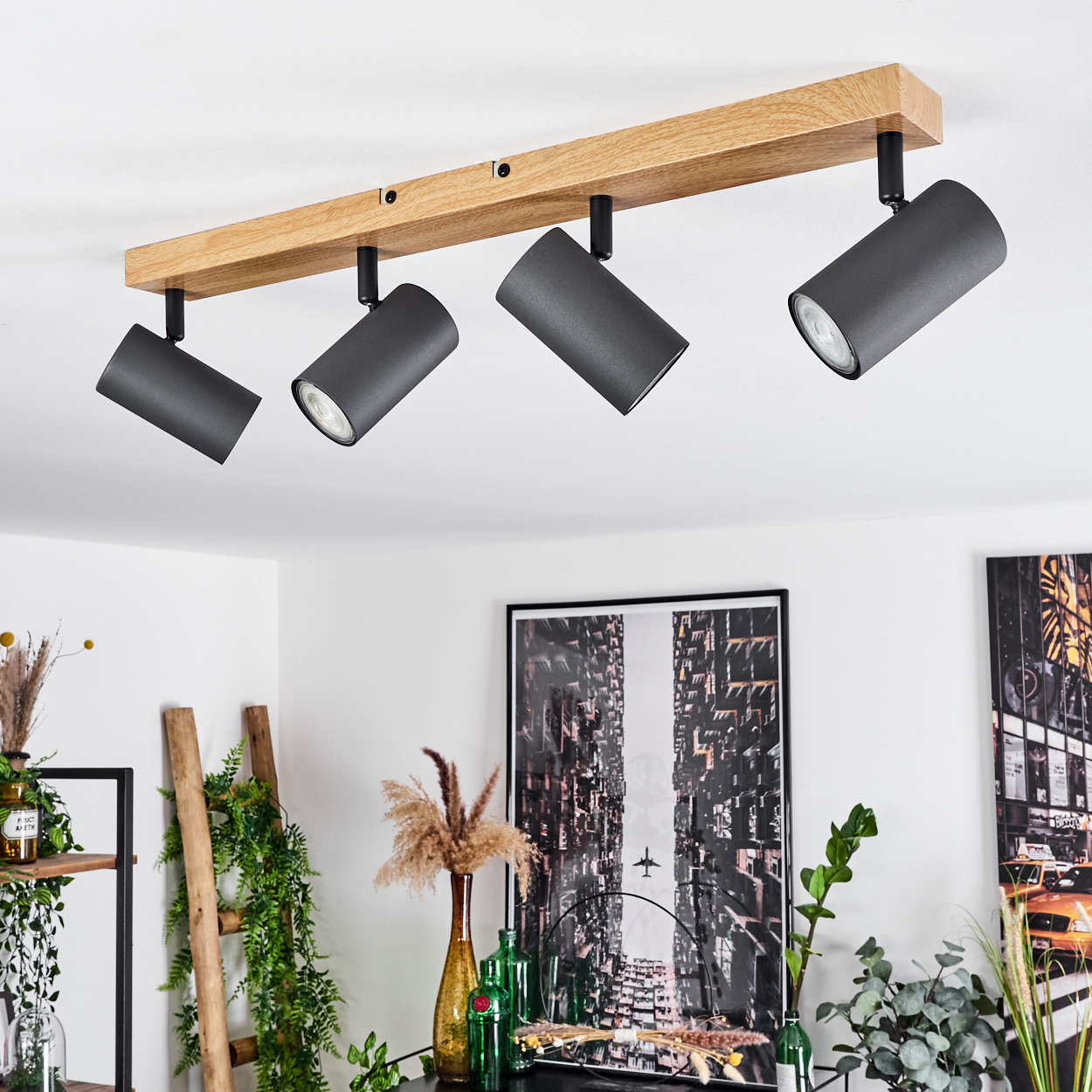 Ein Holzbalken mit vier schwarzen Spots an der Decke montiert.