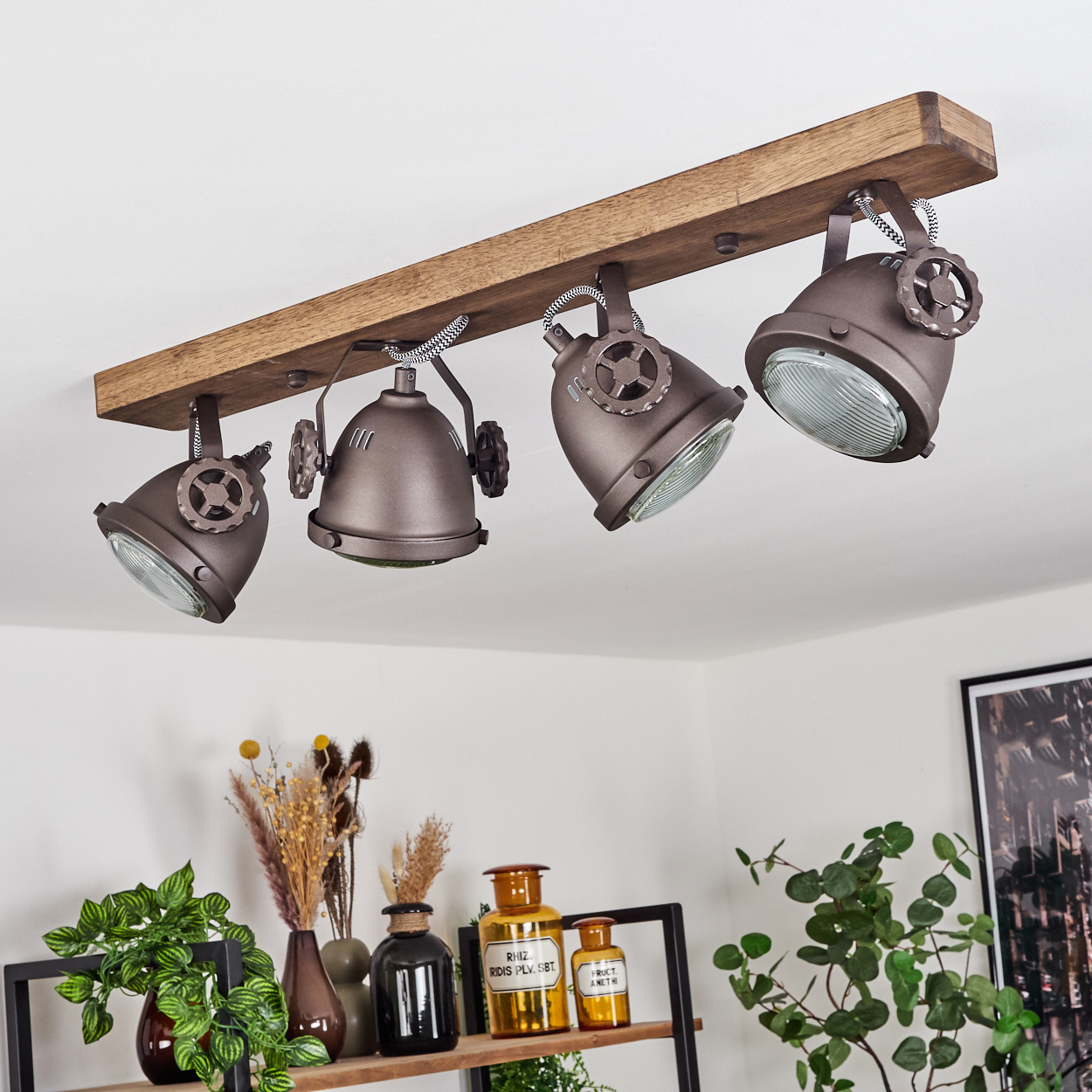 Ein brauner Holzbalken mit vier verstellbaren Leuchten im Industriestil.