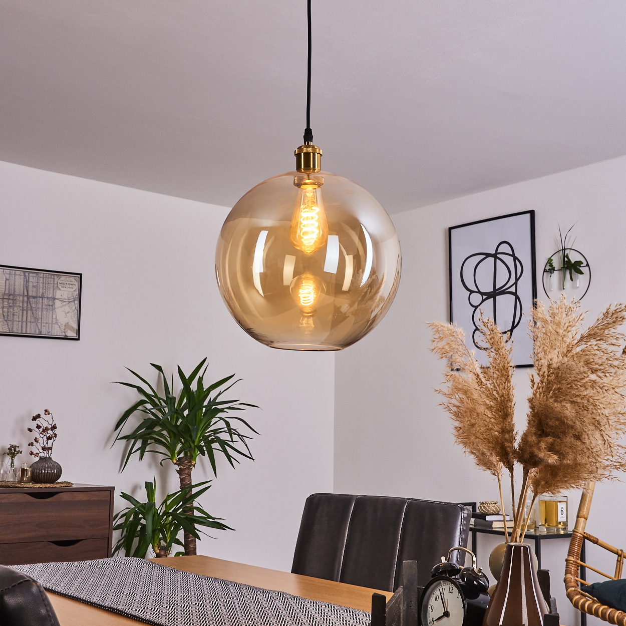 Amber Glas Pendelleuchte mit sichtbarer Glühbirne über einem Esstisch.