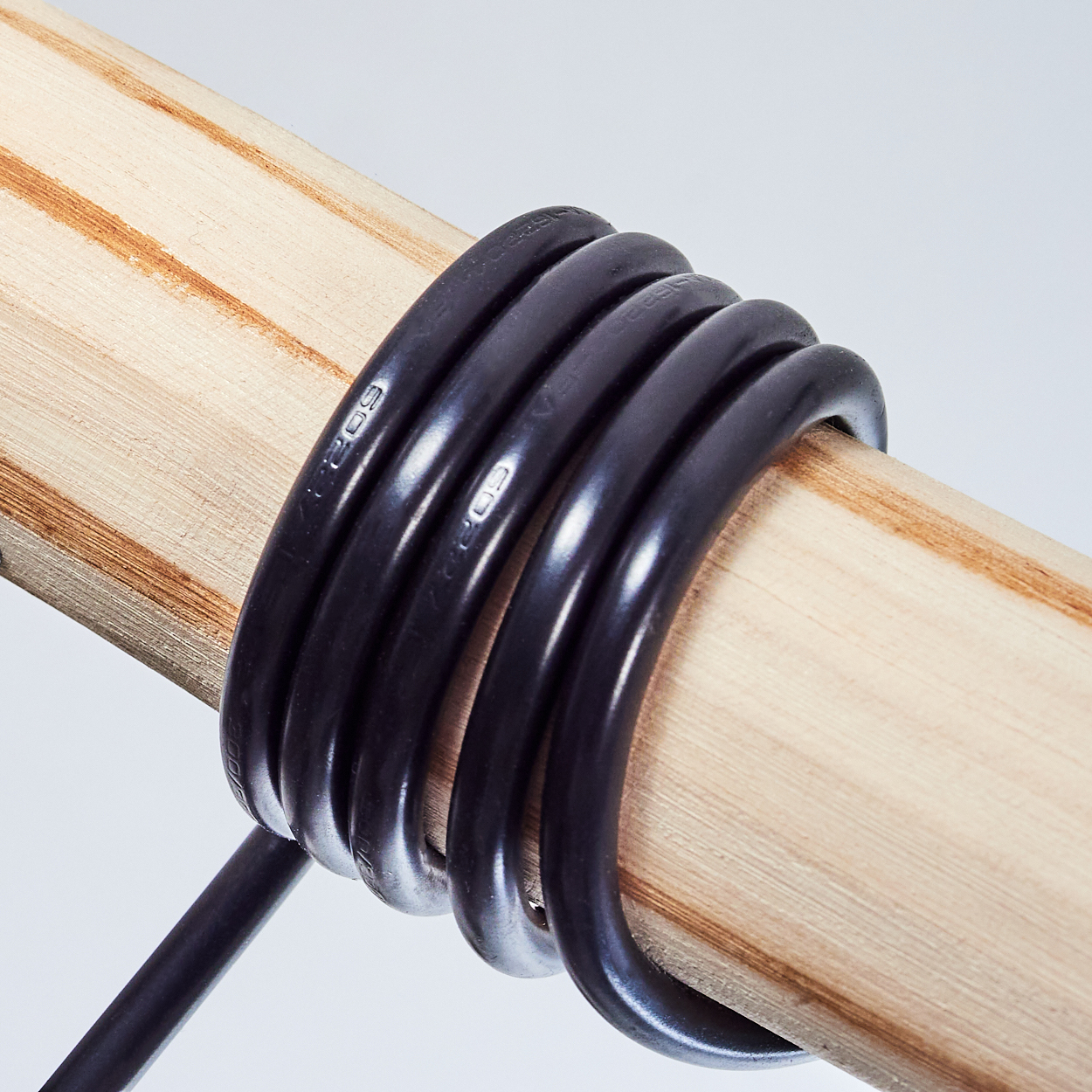 Schwarzes Kabel auf einem Holzstab gewickelt.