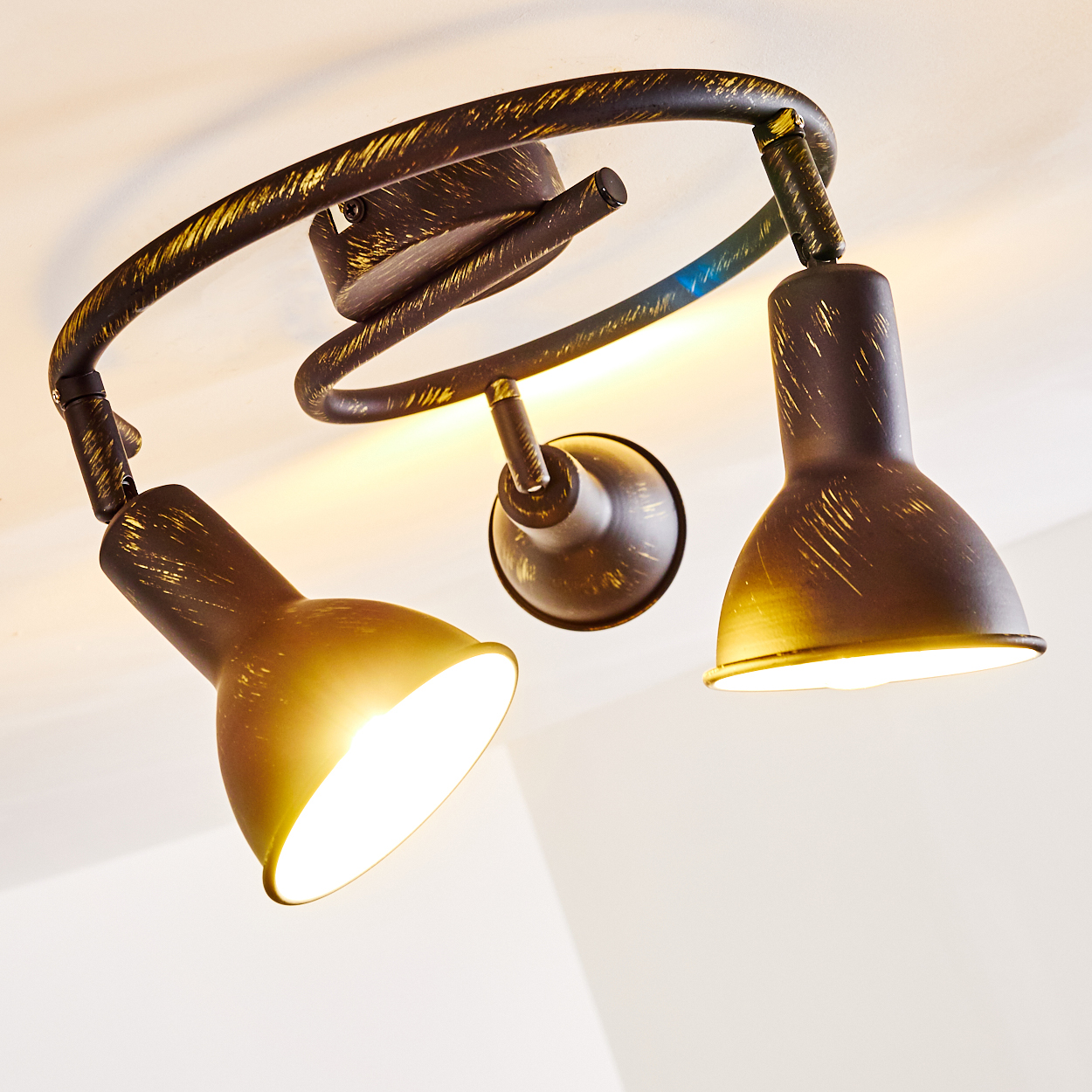 Eine braune Deckenleuchte mit drei verstellbaren Spots und goldenen Akzenten.
