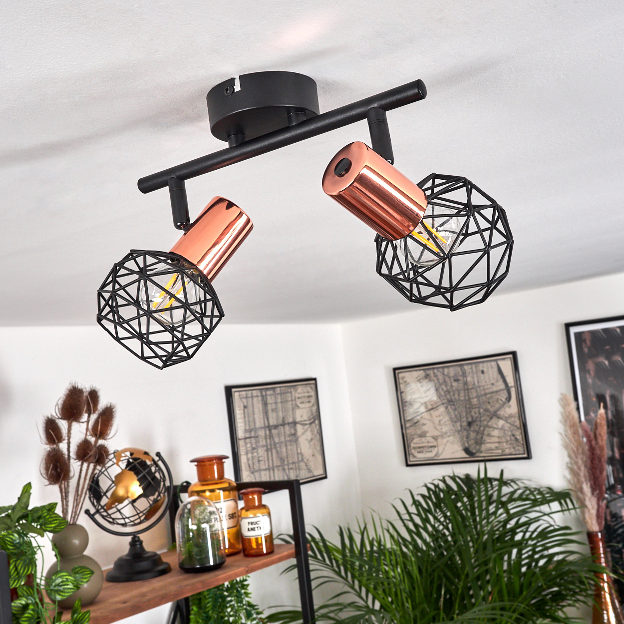 Zwei kupferfarbene Lampen mit schwarzem Drahtkäfig-Schirm an einer schwarzen Deckenleiste.