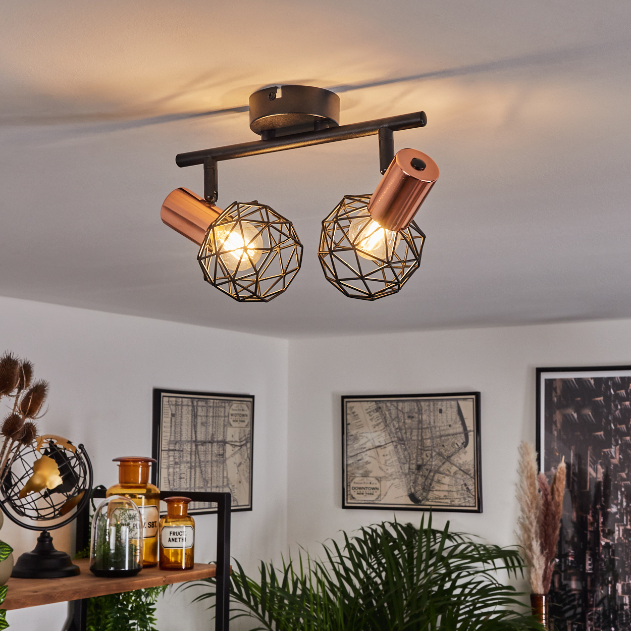 Eine Deckenleuchte mit zwei kupferfarbenen Kappen und schwarzen Drahtkugelschirm-Lampen.