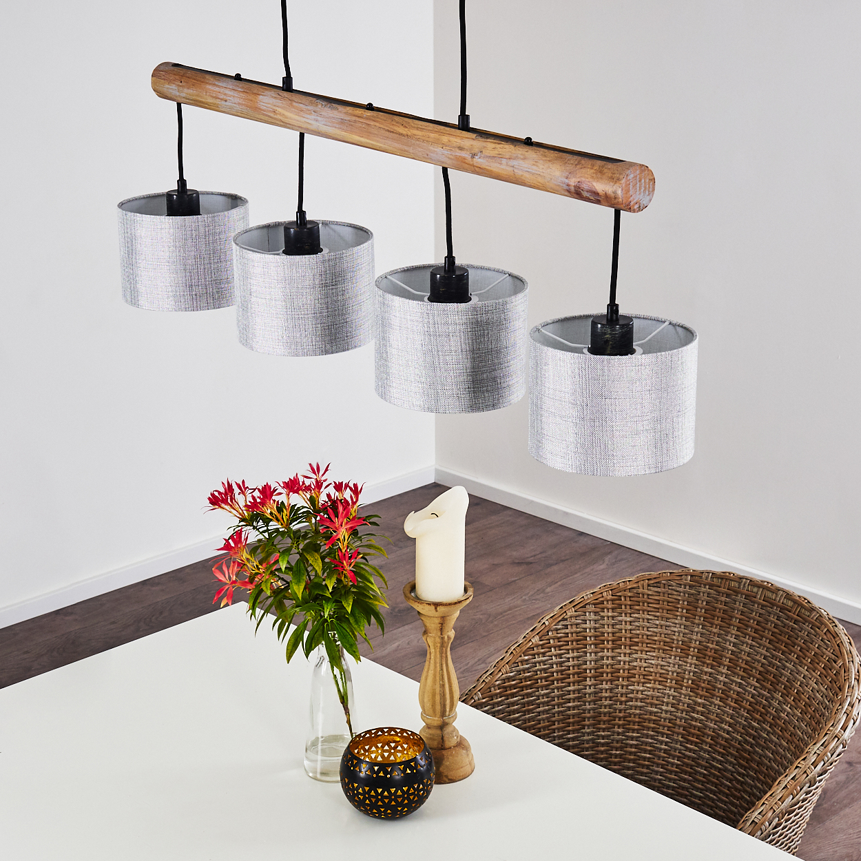 Ein Kronleuchter mit Holzbalken und vier grauen Schirmen hängt über einem Tisch mit Blumen und Kerze.