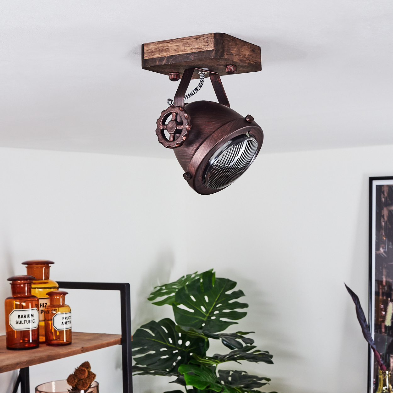 Eine kupferfarbene Pendelleuchte mit Holzdecke und einem Rad zur Einstellung.