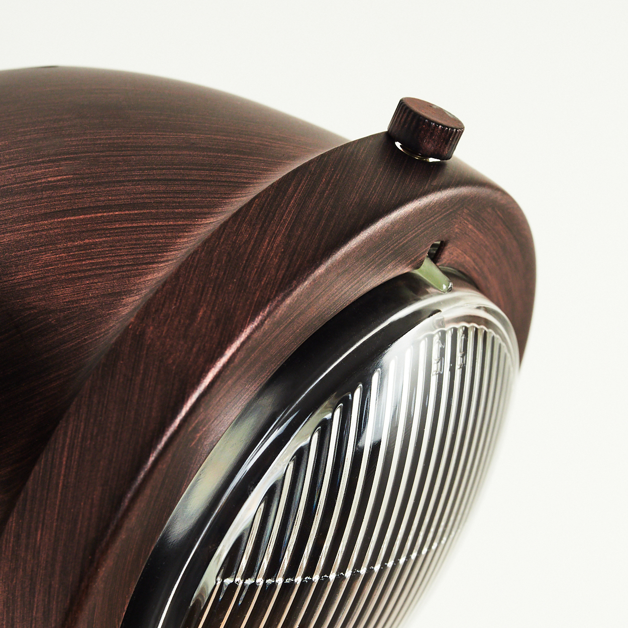 Eine Nahaufnahme einer kupferfarbenen Lampe mit geriffeltem Glas und einem kleinen Knopf.