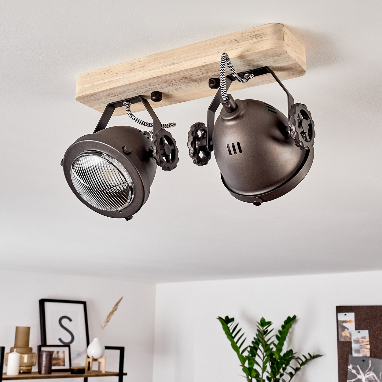 Zwei dunkle, verstellbare Strahler an einem Holzbalken an der Decke.