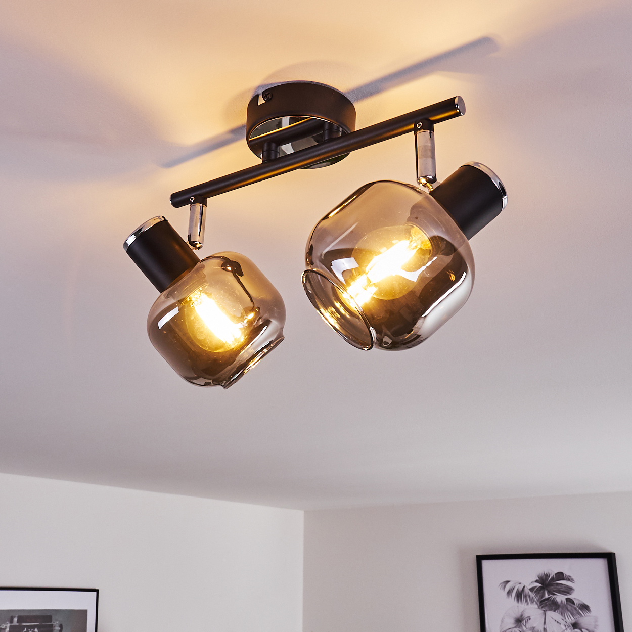 Zwei rauchglas Lampen an einem schwarzen Deckenstrahler, die Decke ist weiß.