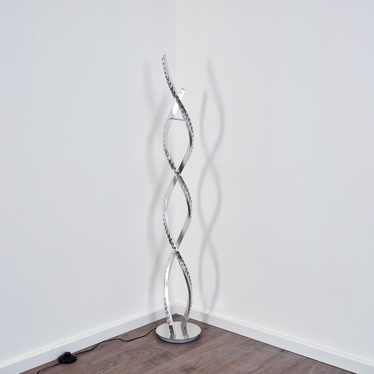 Eine moderne, spiralförmige Stehleuchte mit Kristallakzenten steht in einer Ecke.