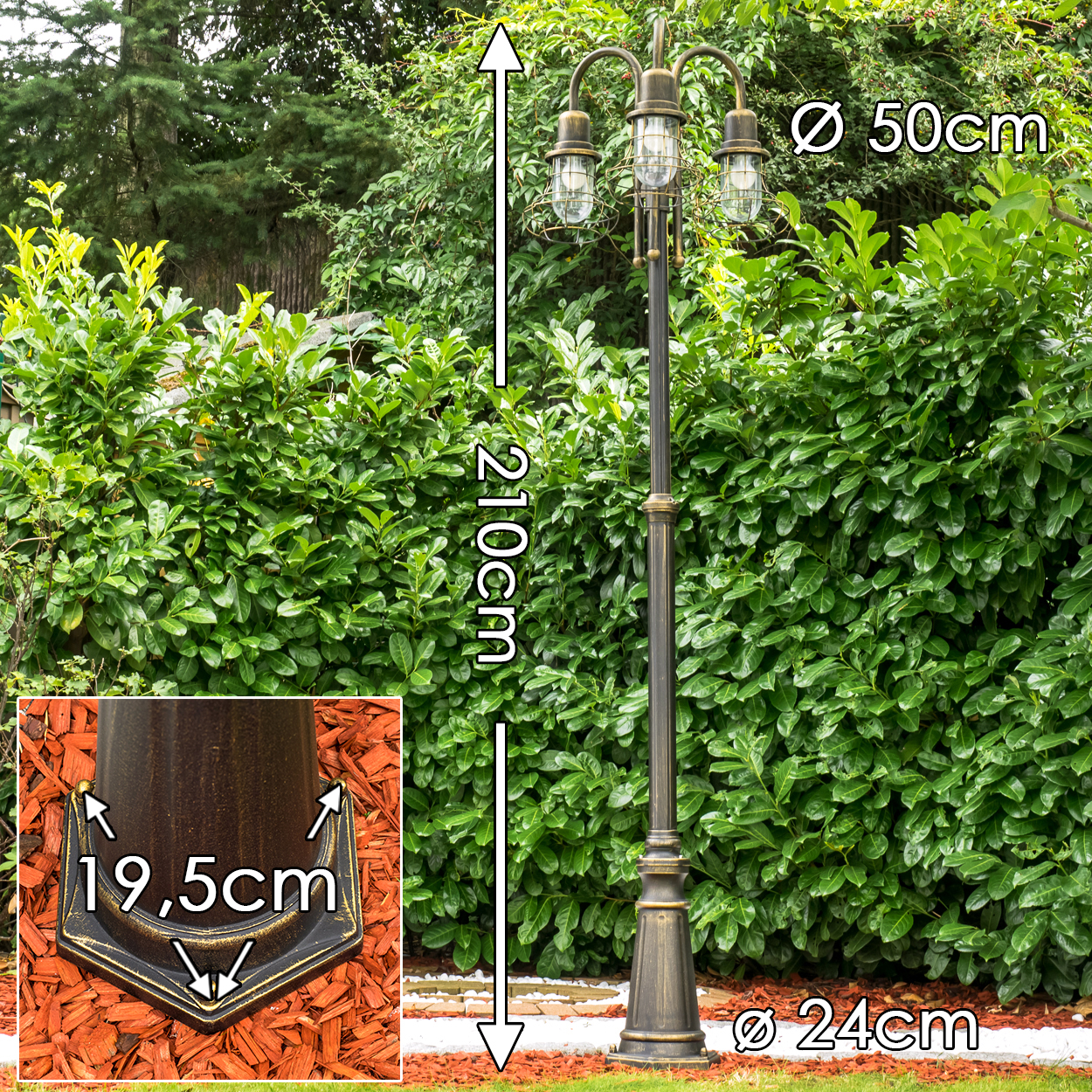 Eine 210cm hohe, dreiflammige Außenlampe in Bronzeoptik steht vor einer grünen Hecke.