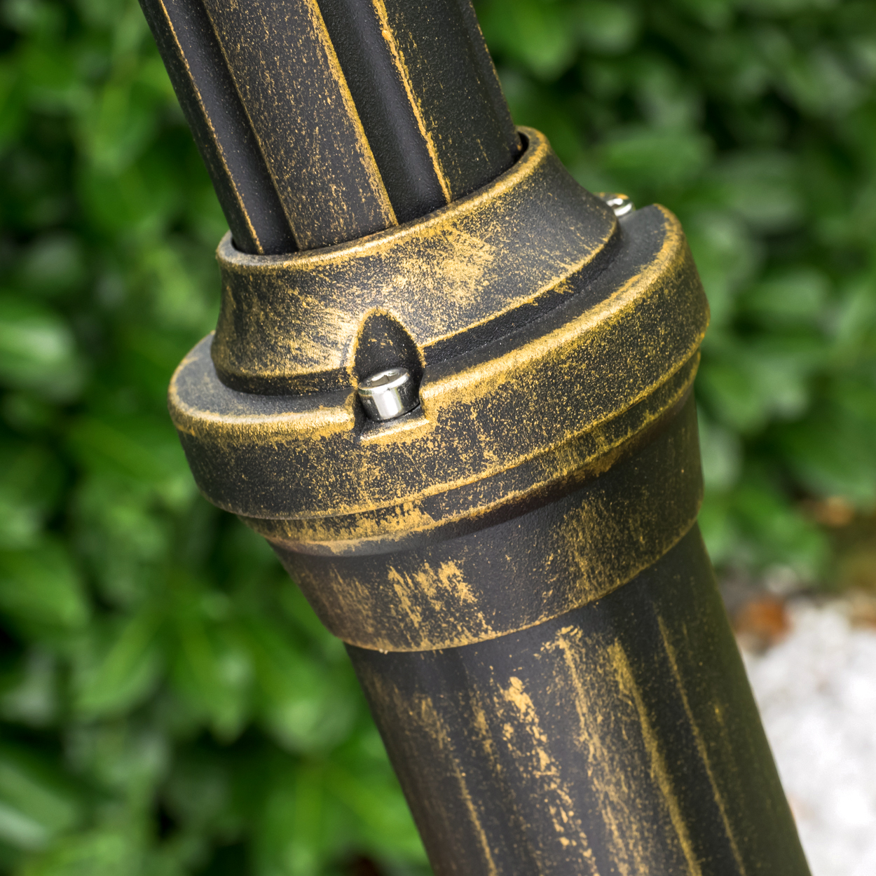 Detailaufnahme einer schwarzen Säule mit goldener Patina und Schrauben.
