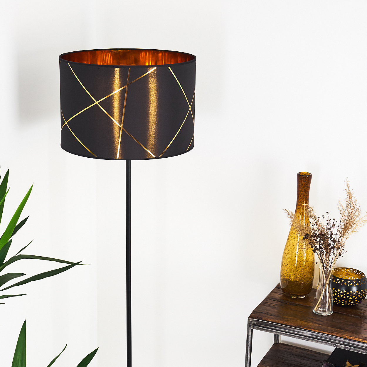 Schwarzer Stehlampe mit goldenem Muster auf schwarzem Schirm und goldenem Inneren.