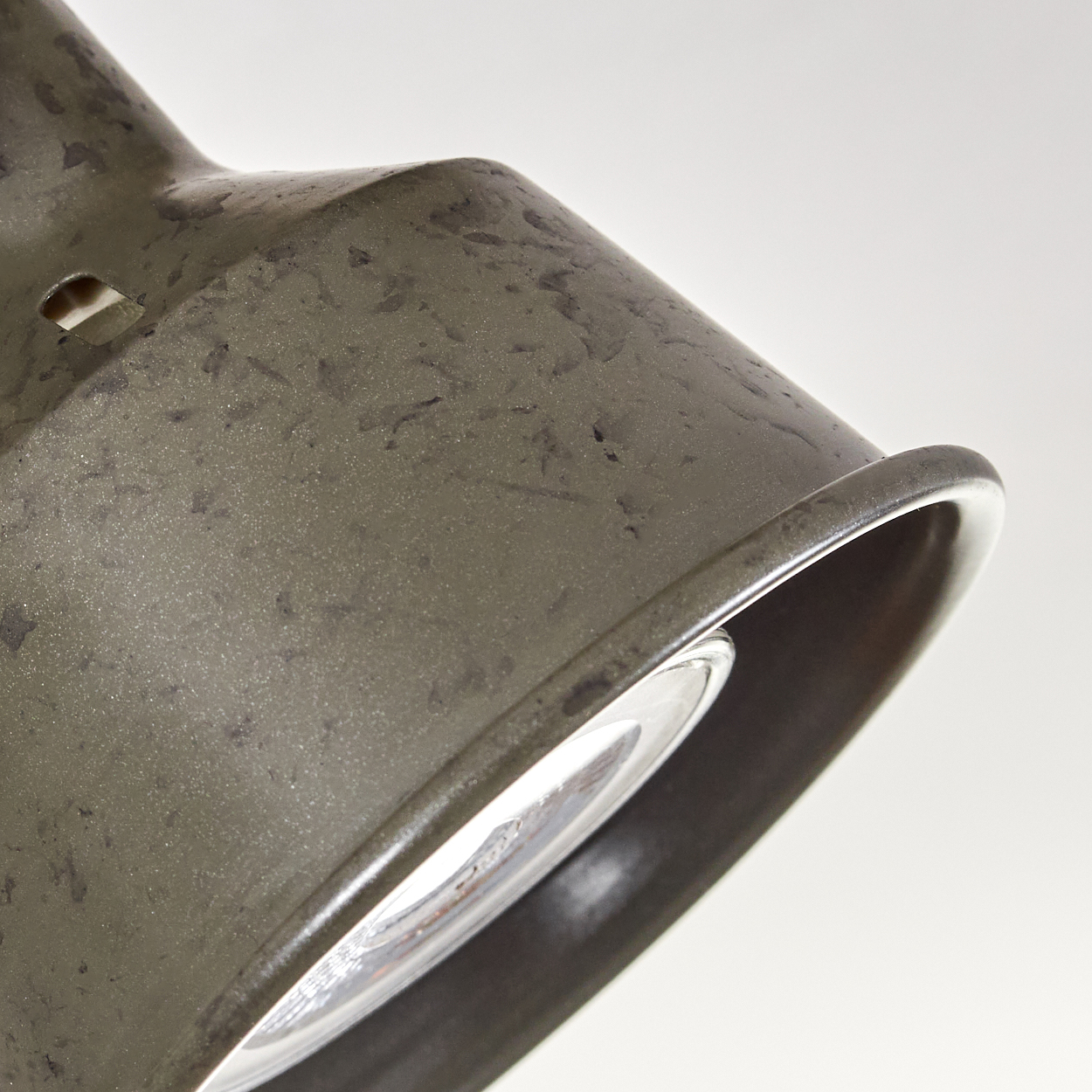 Ein dunkler, metallischer Lampenschirm mit sichtbarer Glühbirne.