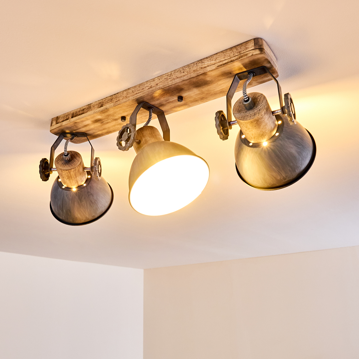 Deckenleuchte mit Holzsockel und drei verstellbaren Metallschirmen.