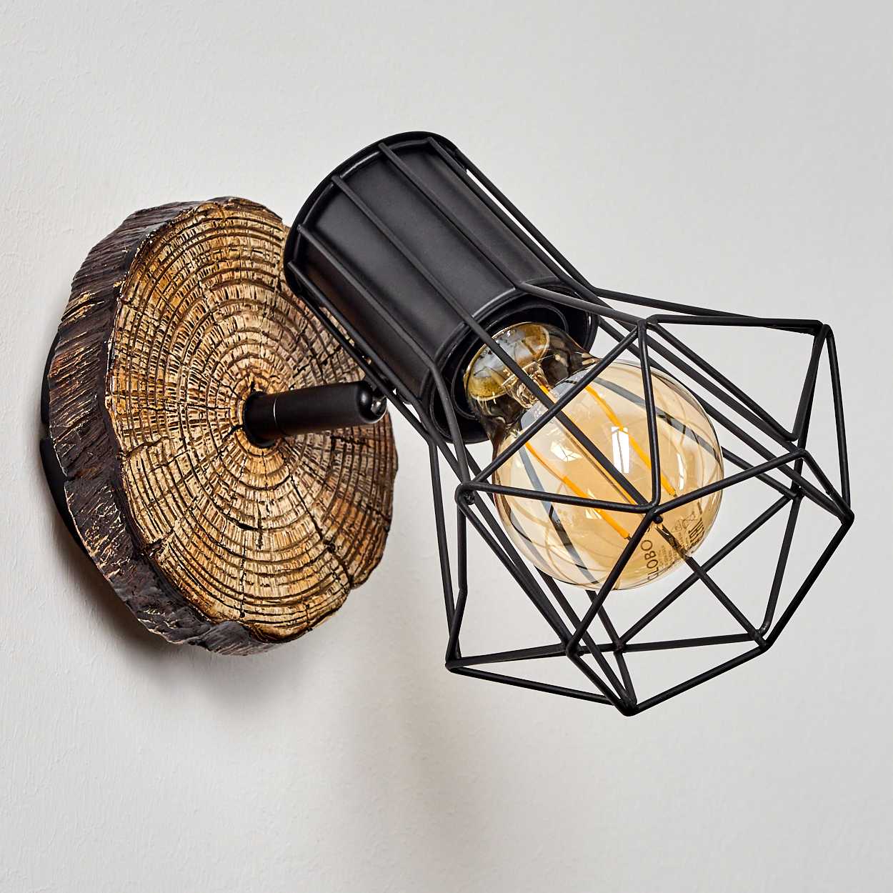 Eine rustikale Wandlampe mit Holzscheiben-Sockel und schwarzem Metallkäfig mit Vintage-Glühbirne.