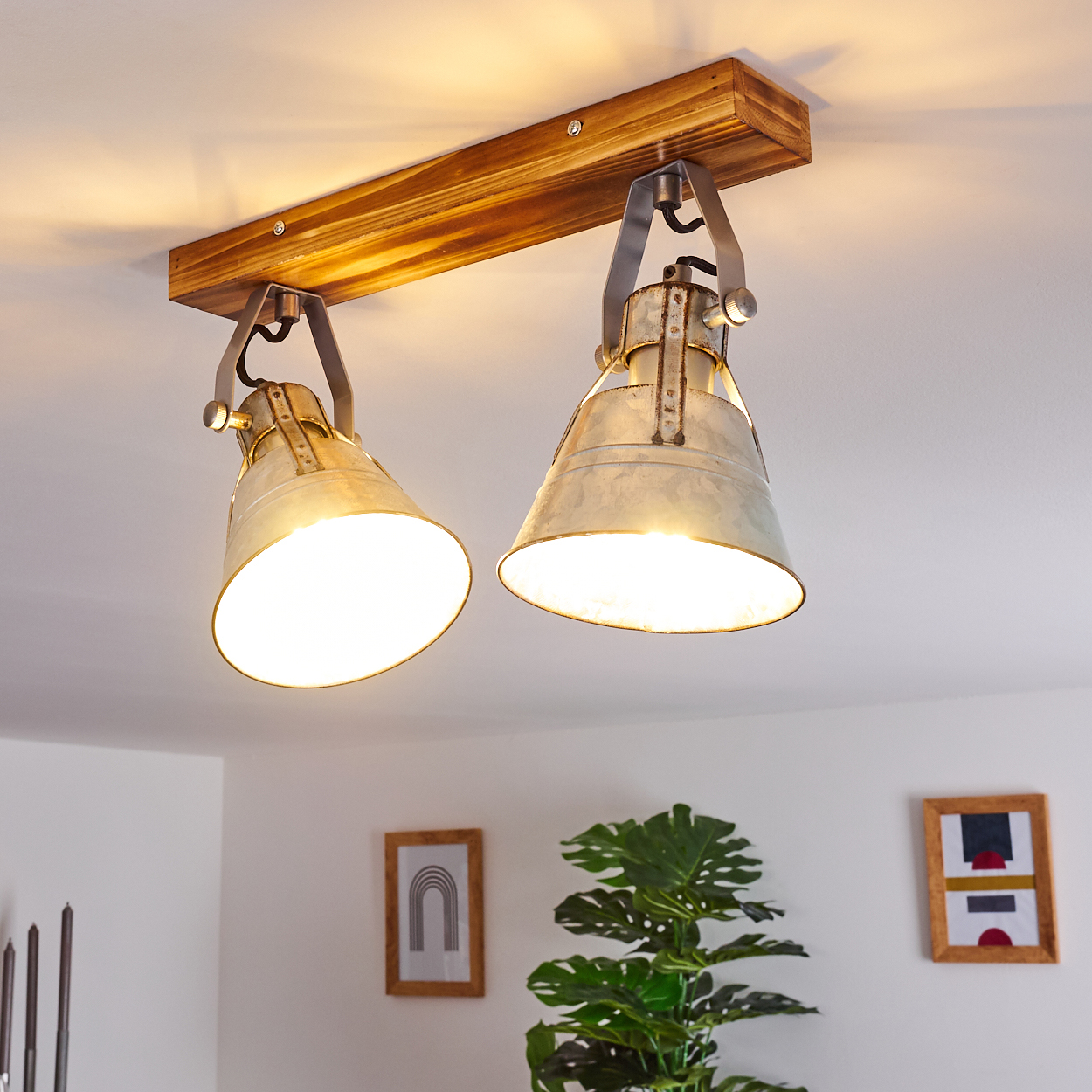 Eine Deckenleuchte mit zwei Lampenschirmen aus Metall und einem Holzbalken.