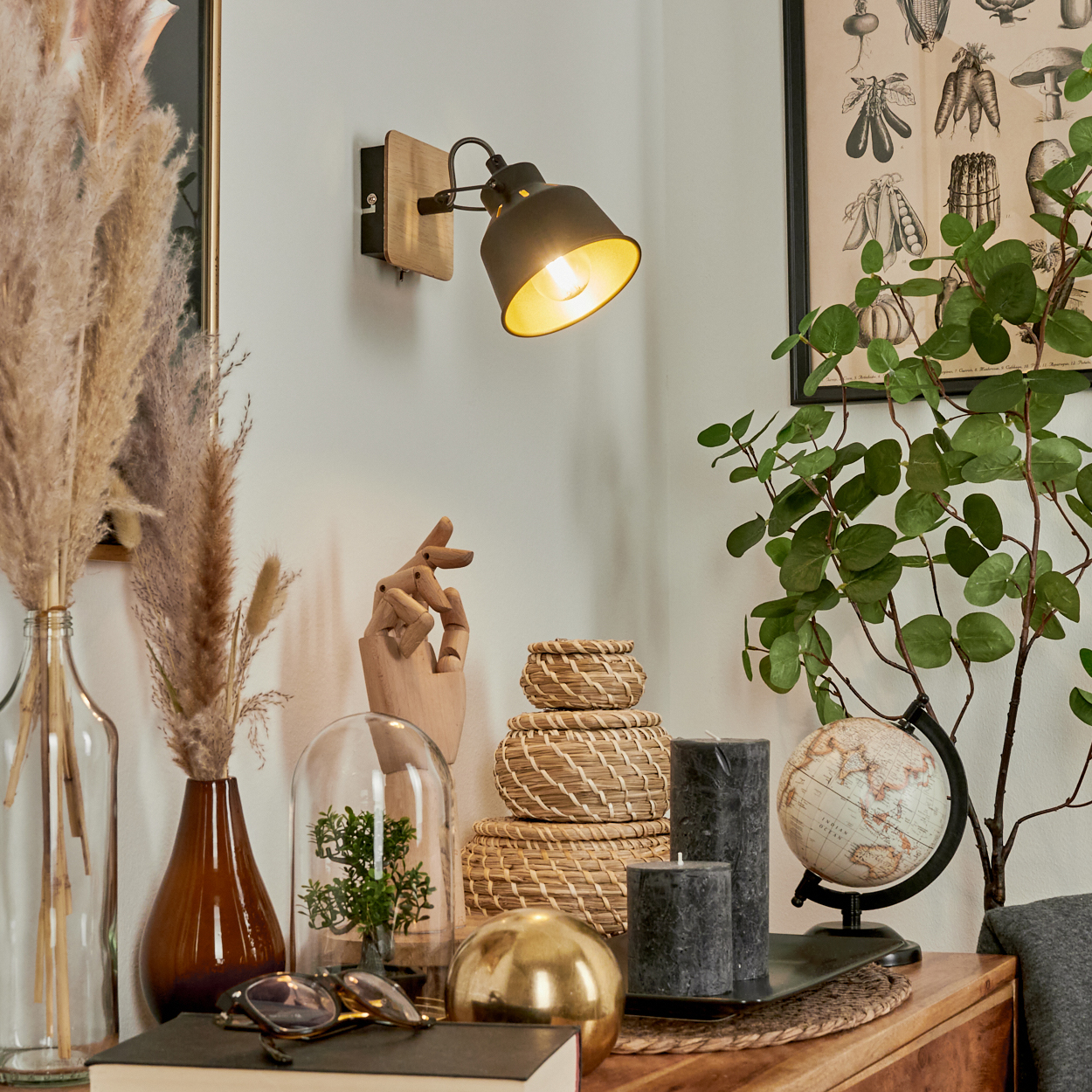Dekorative Objekte auf einem Holzmöbel: Lampe, Pflanzen, Globus, Kerzen, Körbe.