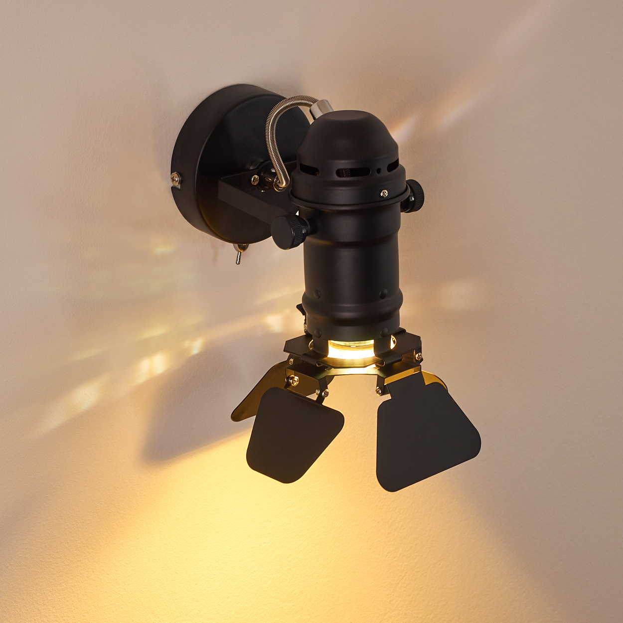 Eine schwarze Wandleuchte im Stil eines Filmstrahlers mit verstellbaren Klappen.