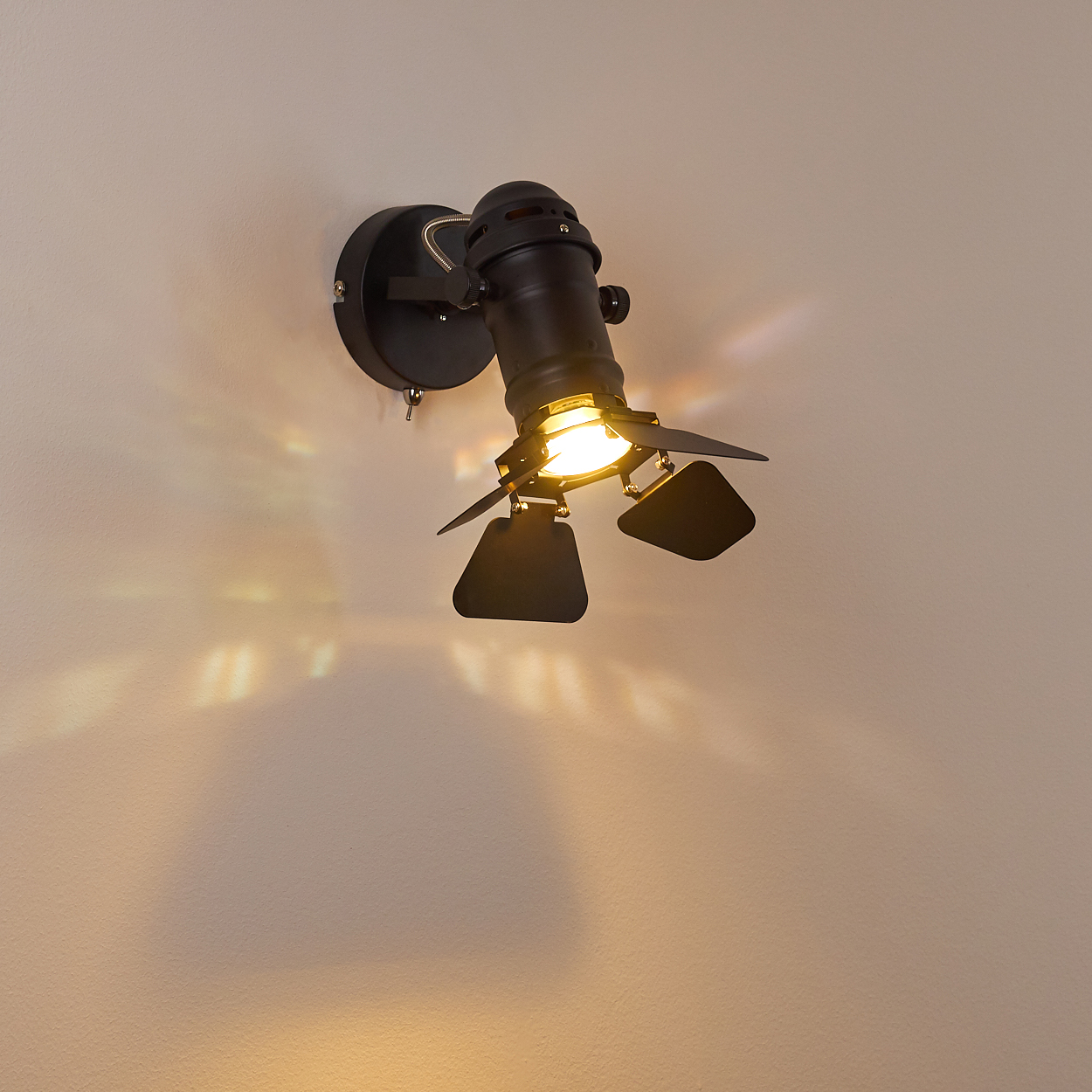 Schwarzer Wandstrahler mit zwei verstellbaren Spots auf einer hellen Wand.