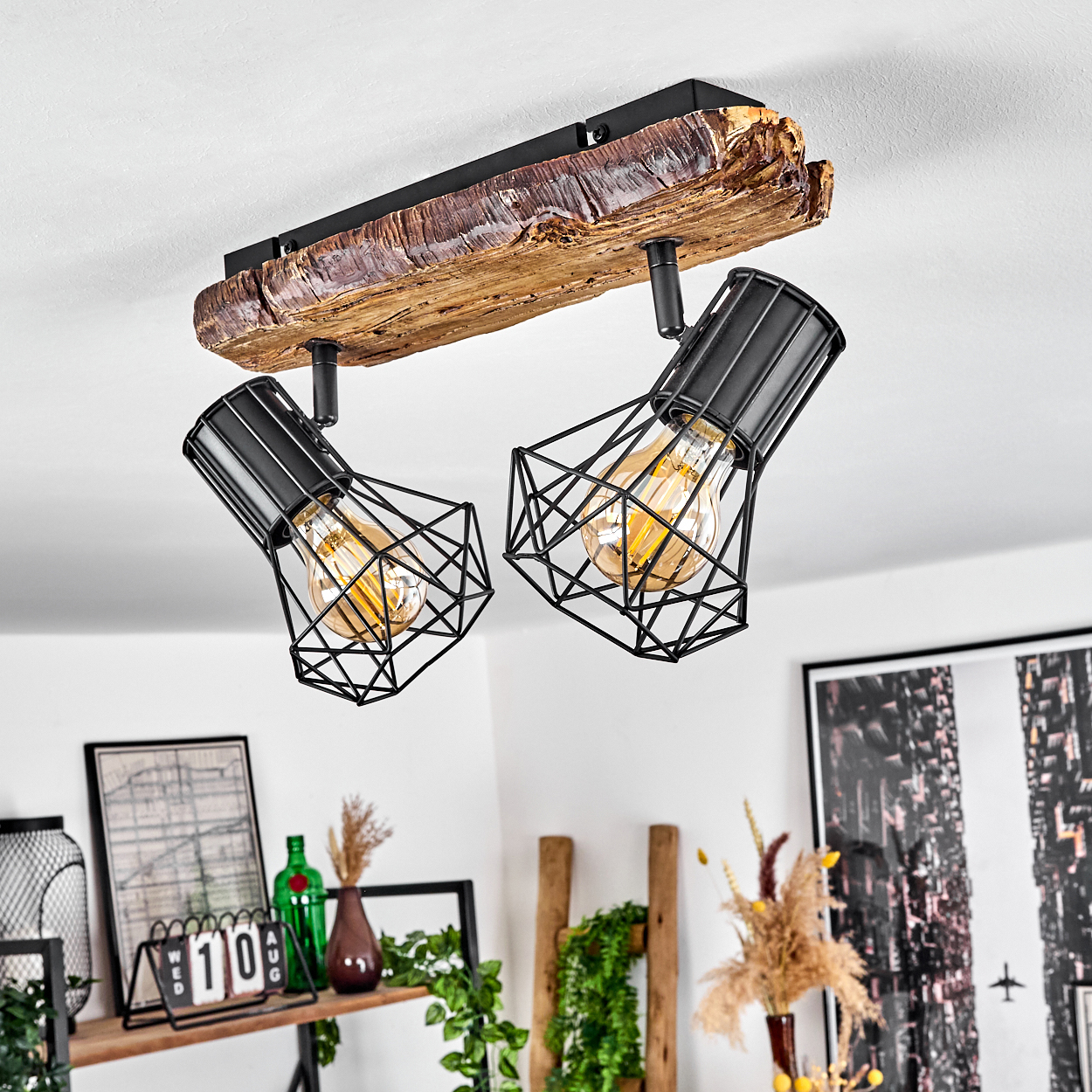 Deckenleuchte mit Holzstamm und zwei schwarzen Drahtkörben mit Glühbirnen.