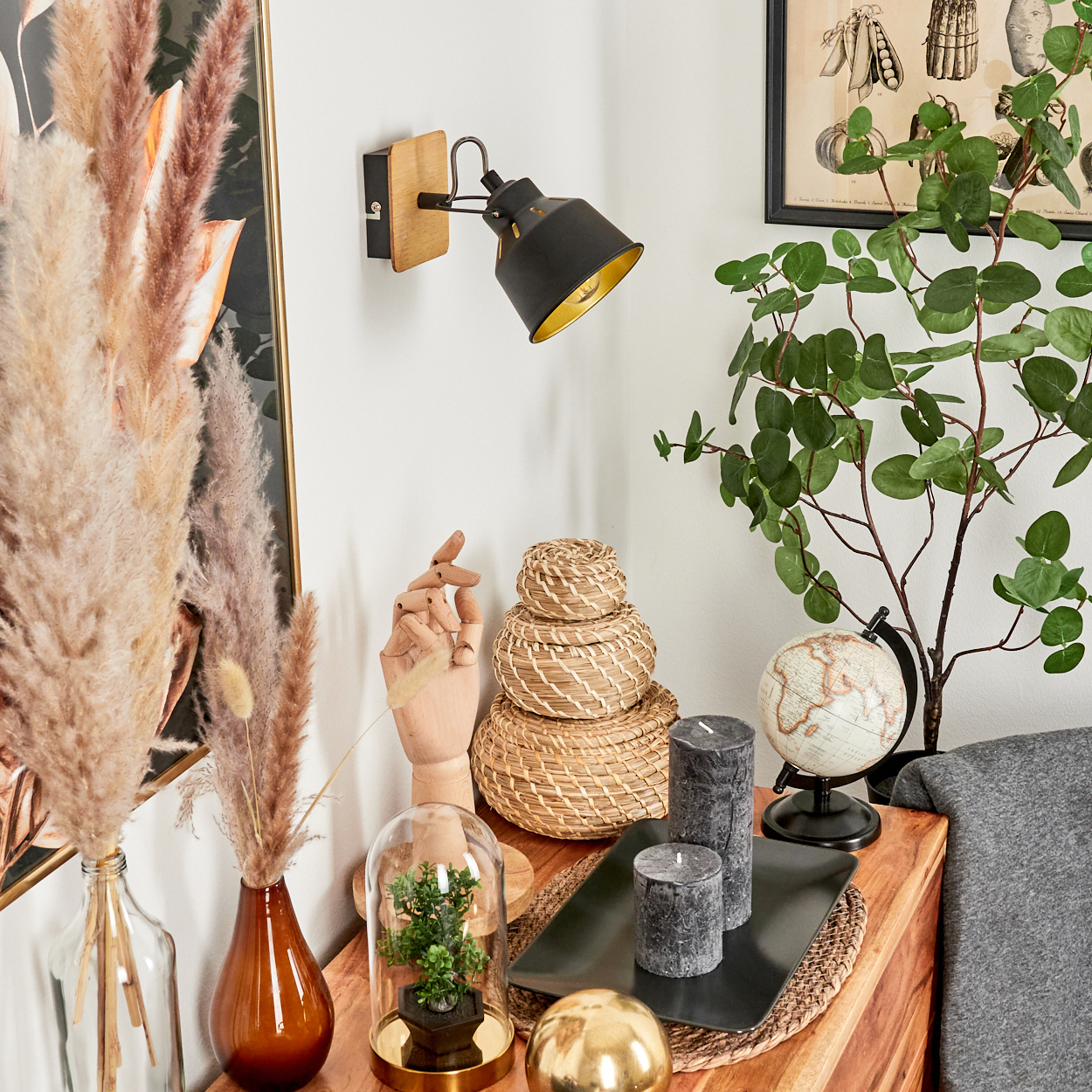 Ein Nachttisch mit Deko: Lampe, Pflanzen, Kerzen, Globus und Körbe.