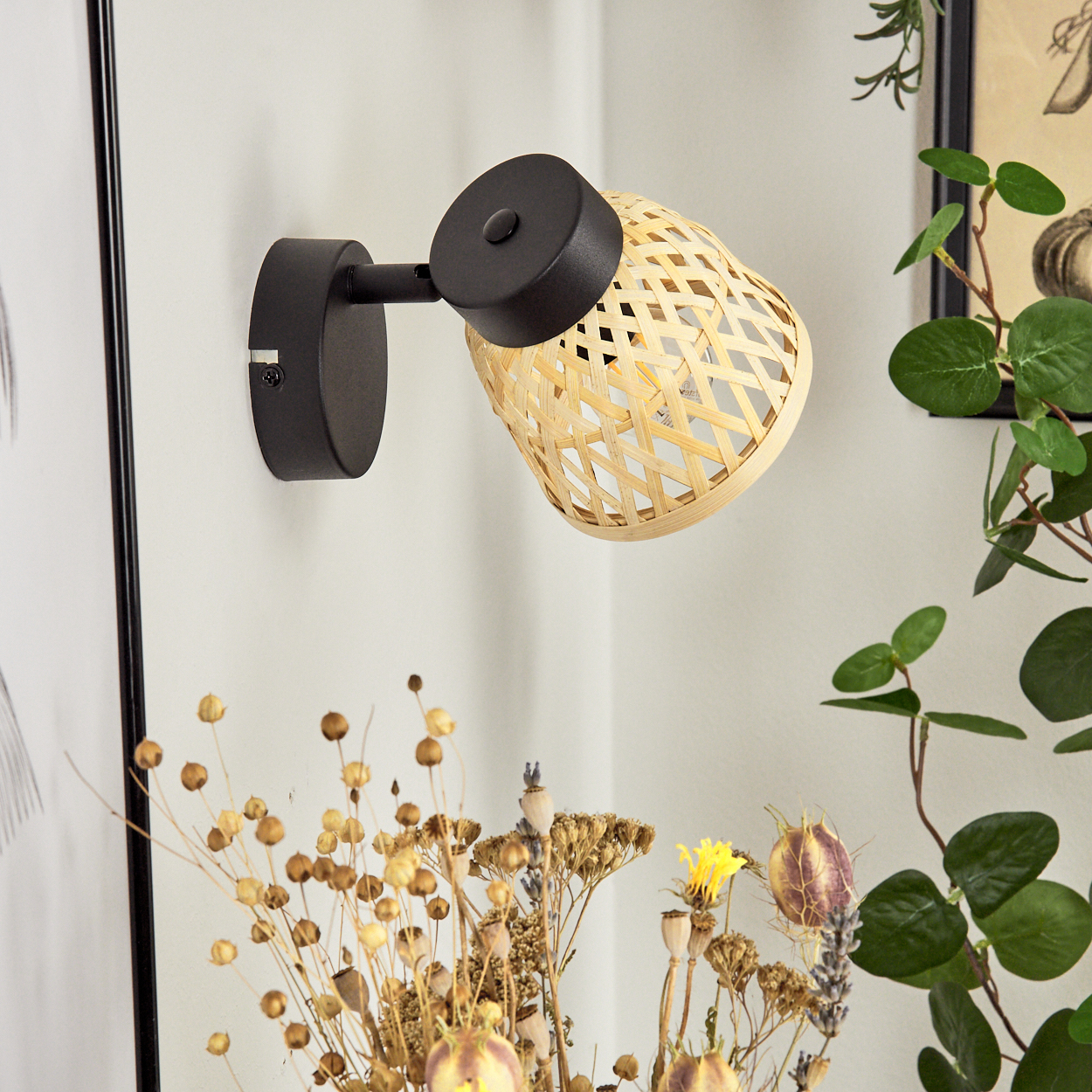 Wandleuchte mit Bambus-Schirm und schwarzem Arm, daneben Trockenblumen.