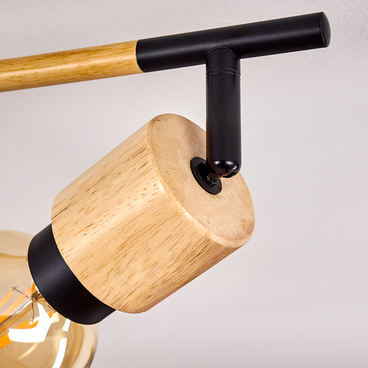 Deckenleuchte mit Holz- und schwarzen Metallteilen. Glühbirne sichtbar.