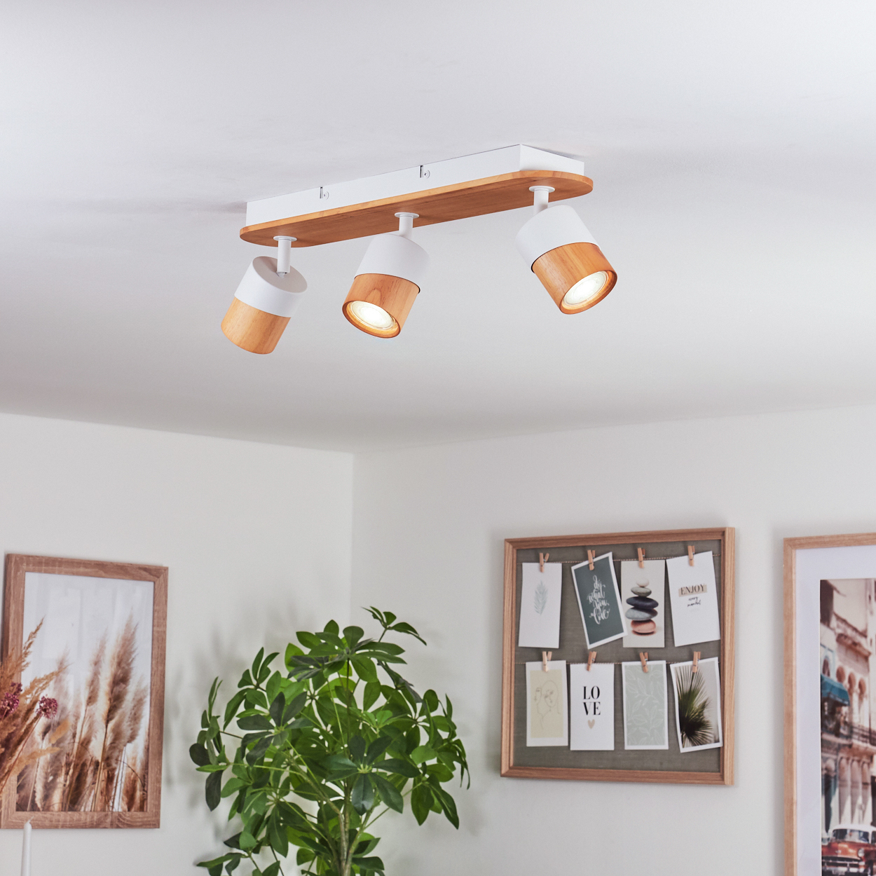 Eine Deckenleuchte in Weiß und Holz mit drei verstellbaren Strahlern ist an der Decke montiert.