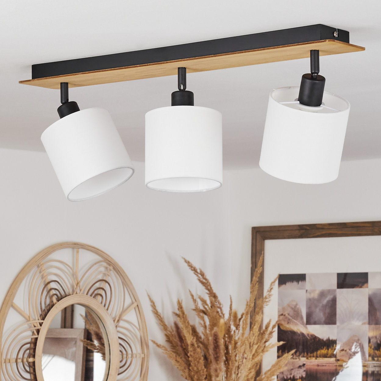 Eine Deckenleuchte mit drei wei ßen Lampenschirmen an einem Holz- und schwarzen Metallbalken.
