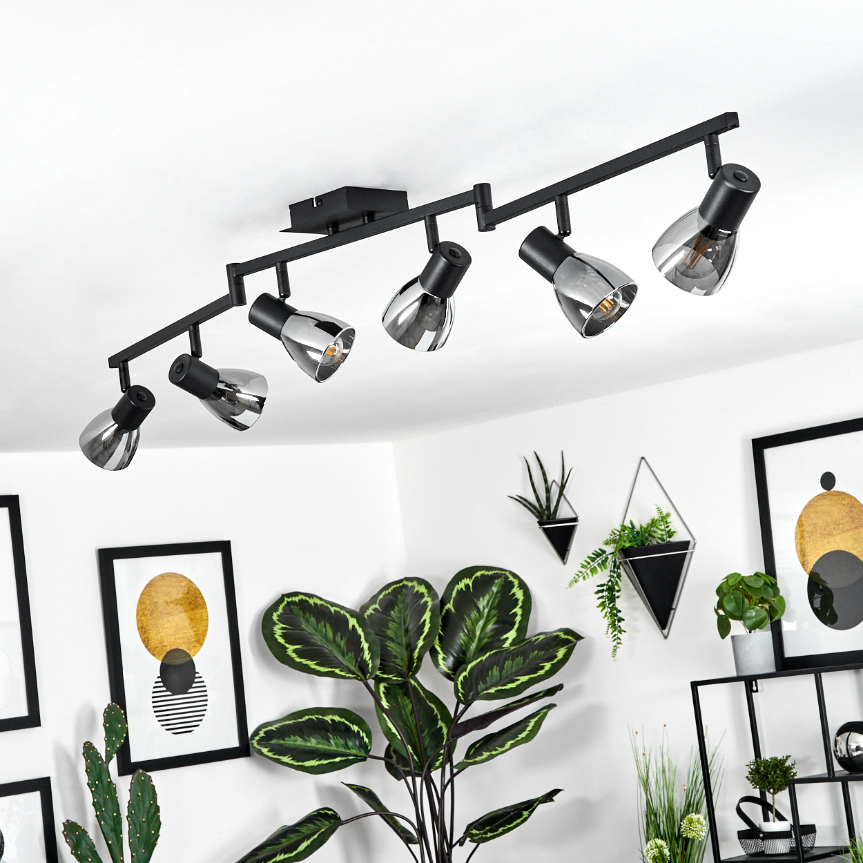 Schwarz einstellbarer Deckenstrahler mit sechs Lampen über Zimmerpflanzen und Kunst.
