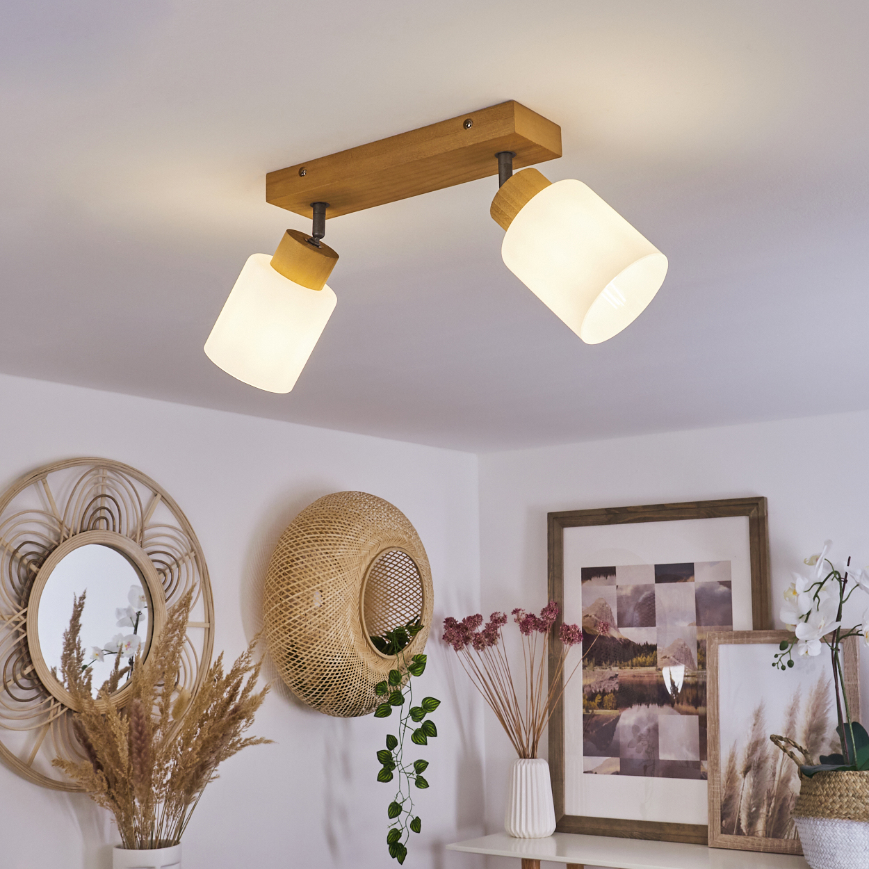 Deckenleuchte aus Holz mit zwei Glaslampenschirmen über Wanddeko.