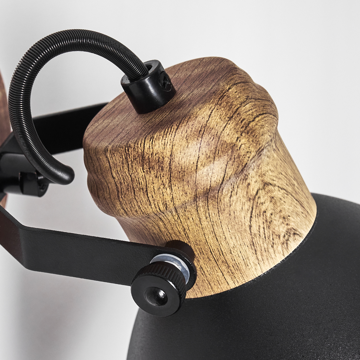 Nahaufnahme einer Lampe mit Holzdekor und schwarzem Metallgestell, flexibler Schlauch.