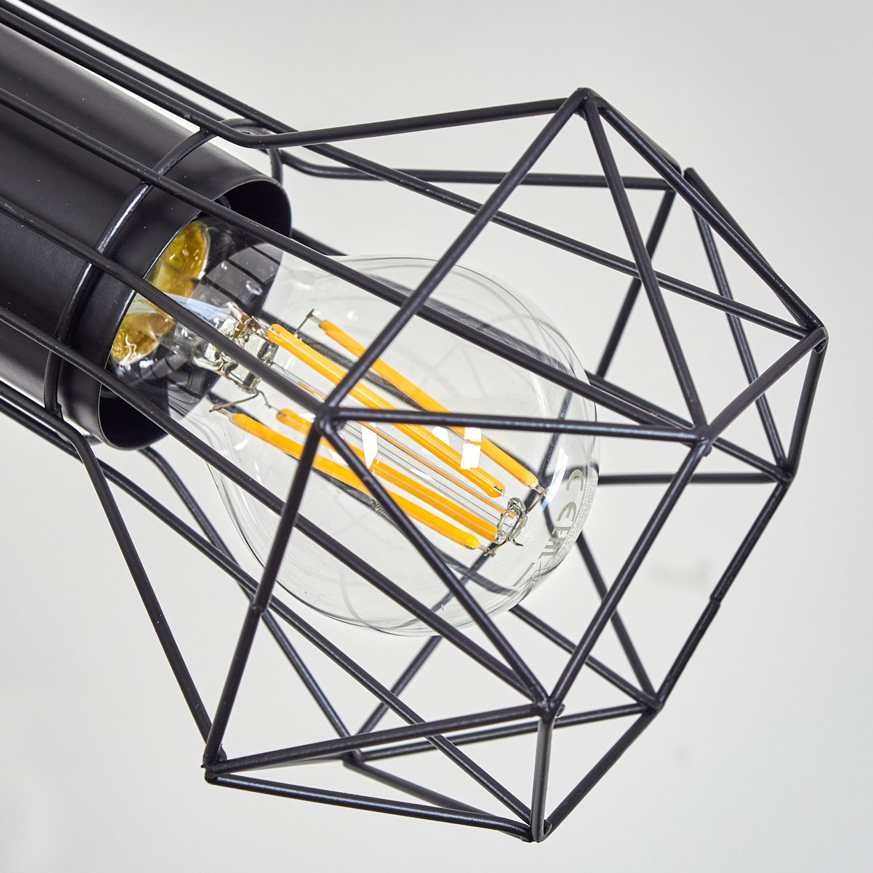 Eine Glühbirne mit orangefarbenen LED-Filamenten in einem schwarzen geometrischen Drahtkäfig.
