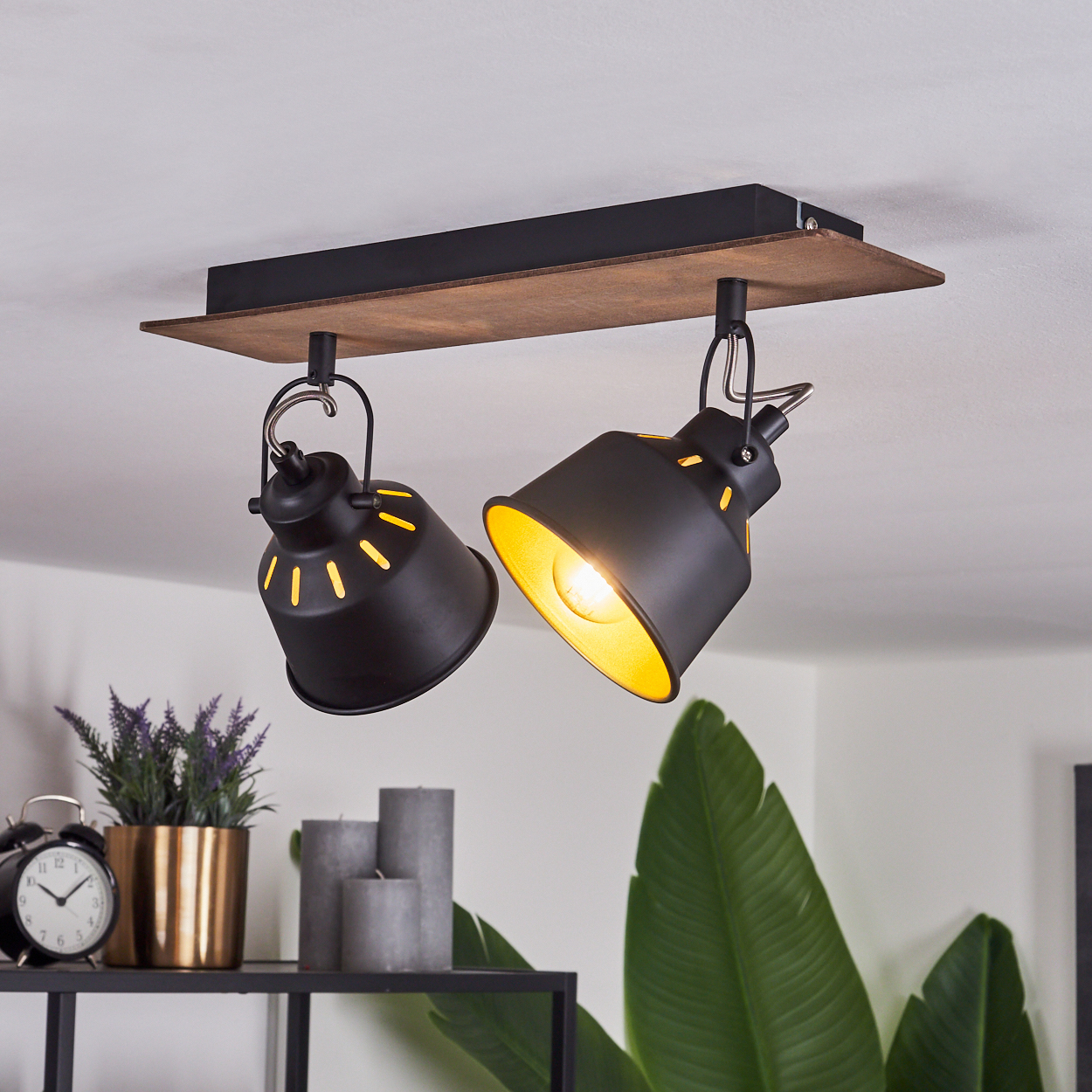 Schwarze Deckenleuchte mit Holzsockel, zwei verstellbare Lampenschirme mit gelben Innenseiten.