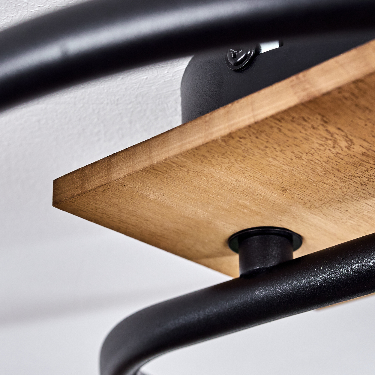 Holzregal mit schwarzen Metallrohren an einer weißen Wand.