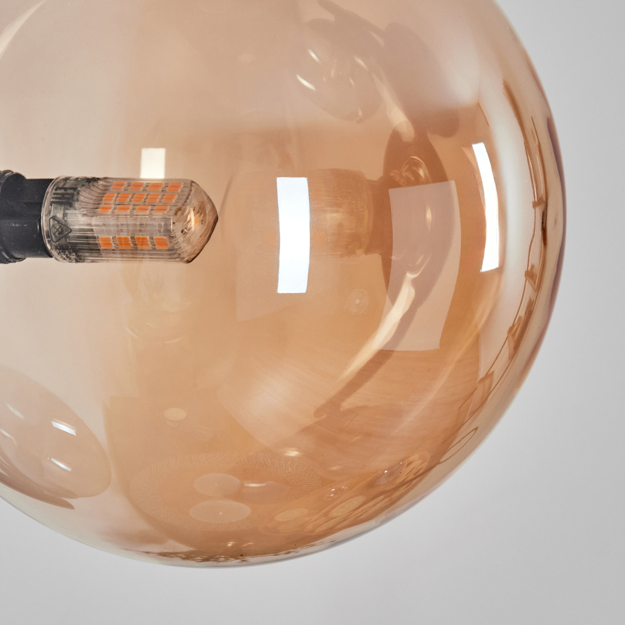 Eine bernsteinfarbene Glühbirne mit sichtbaren LED-Streifen, Nahaufnahme.