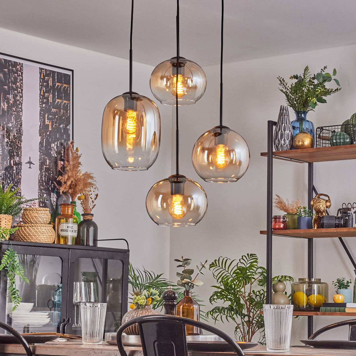 Vier bernsteinfarbene Glaspendelleuchten hängen über einem Holztisch mit Gläsern.