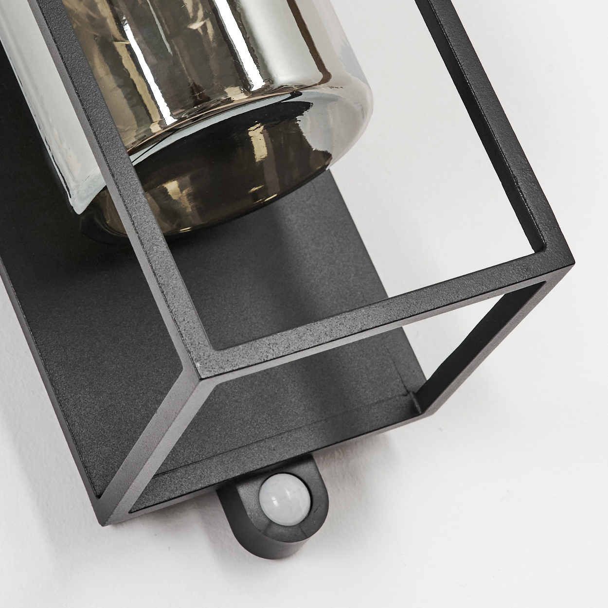 Schwarze Wandleuchte mit Glaszylinder und Bewegungsmelder.