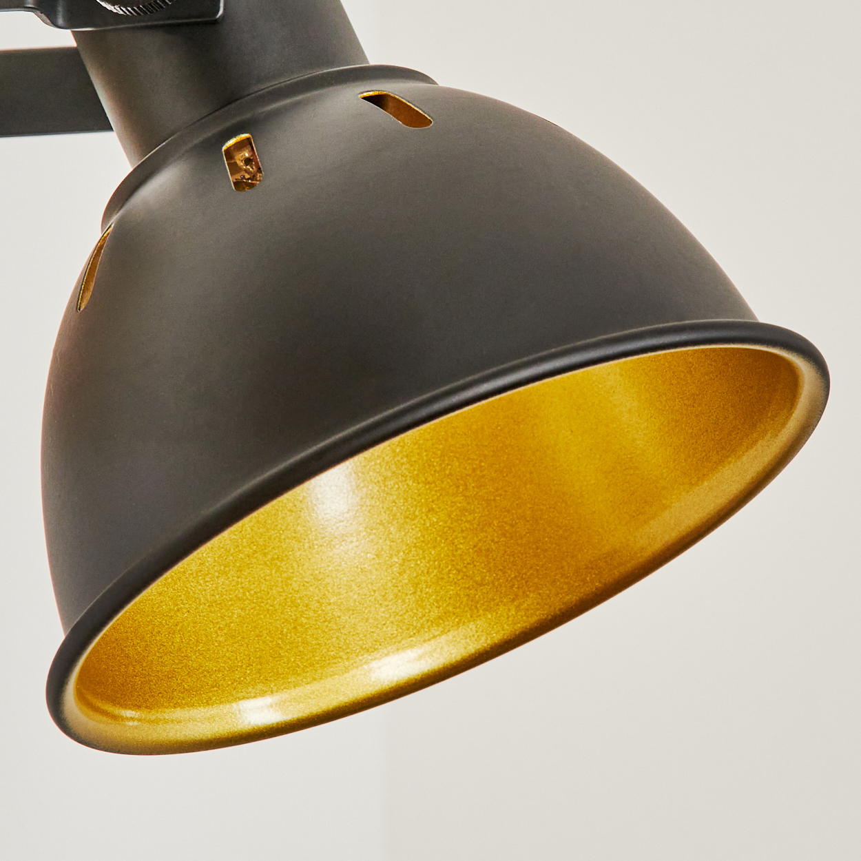 Schwarzer Lampenschirm mit goldenem Inneren und Lüftungsschlitzen.