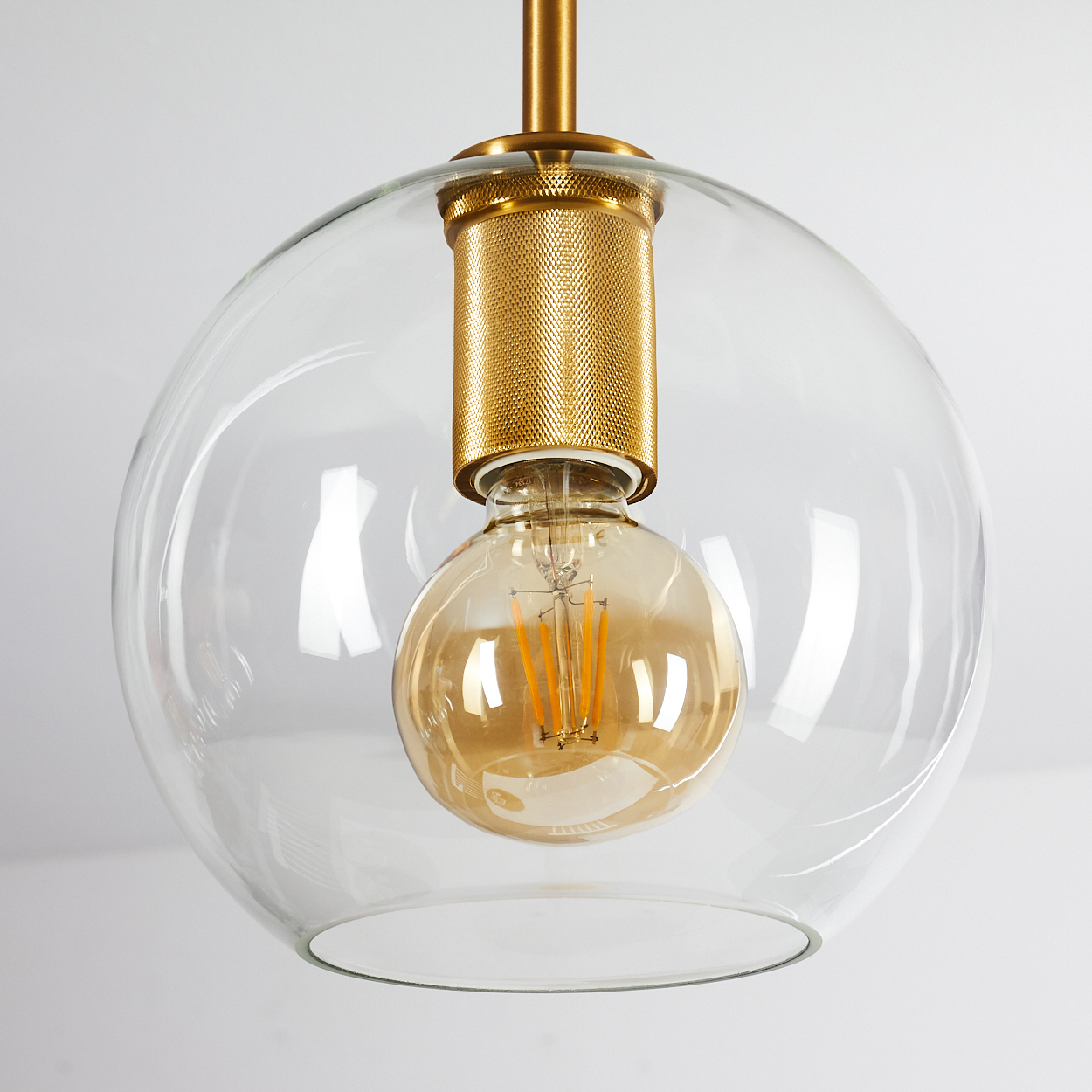 Eine goldene Glühbirne in einem klaren Glasglobus mit messingfarbener Fassung.