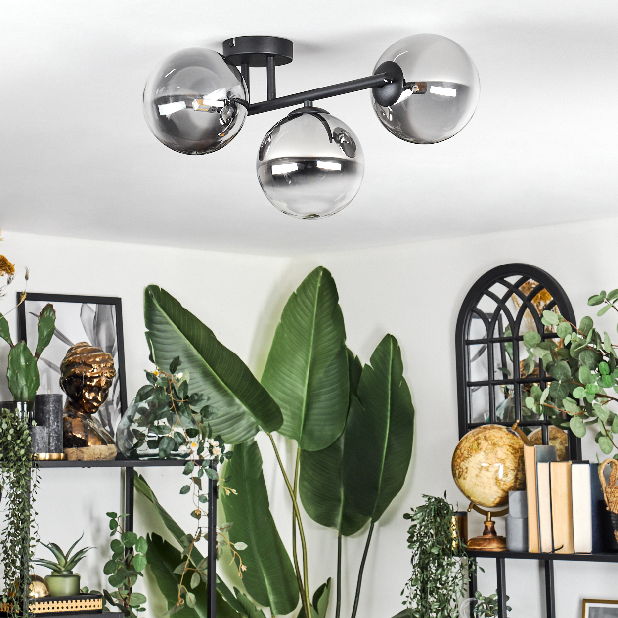 Moderne Deckenleuchte mit drei rauchglas Kugeln über Pflanzen und Dekor.