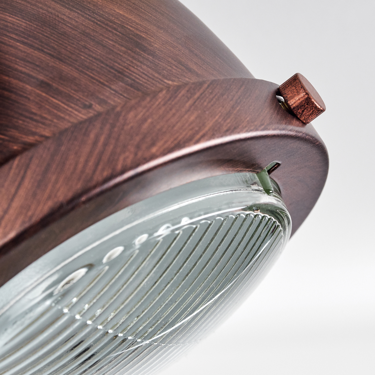 Nahaufnahme einer kupferfarbenen Lampe mit Glasabdeckung und Schraube.