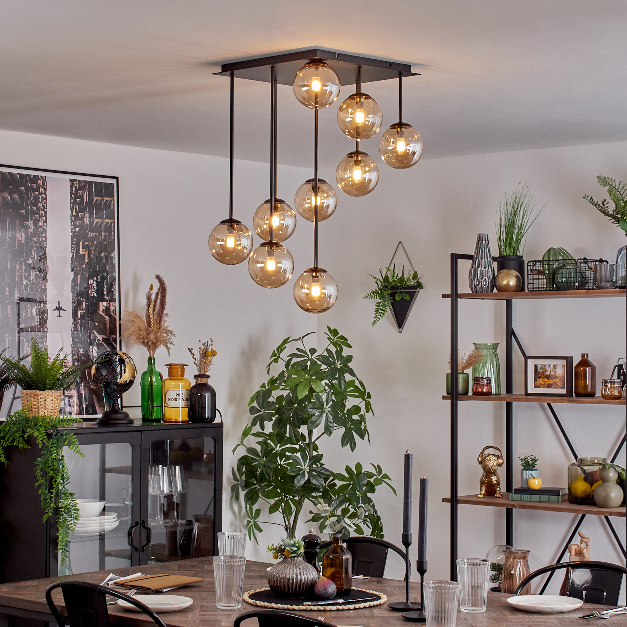 Ein Esszimmer mit einem Holztisch, Gläsern, Kerzen und einer Hängeleuchte.