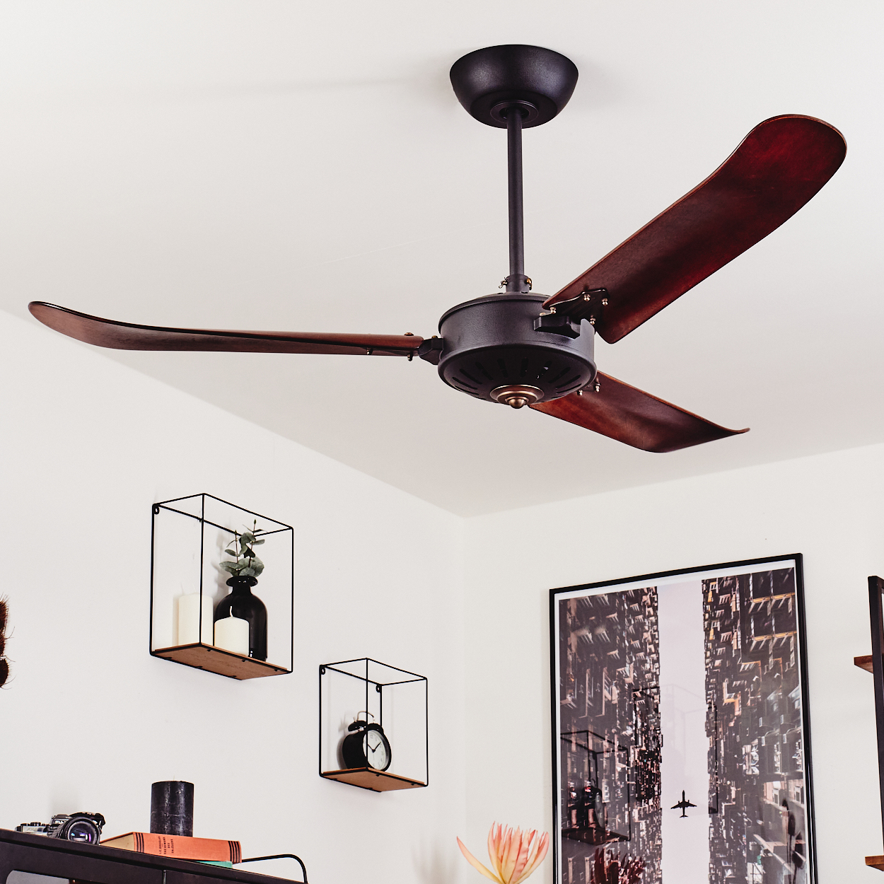 Dunkler Deckenventilator mit Holzflügeln über zwei Wandregalen.