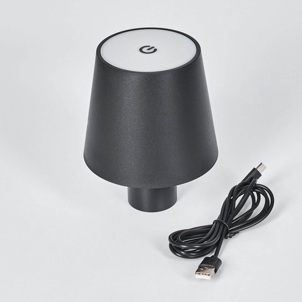 Schwarze Lampe mit Touch-Ein/Aus-Symbol und USB-Kabel auf weißem Hintergrund.