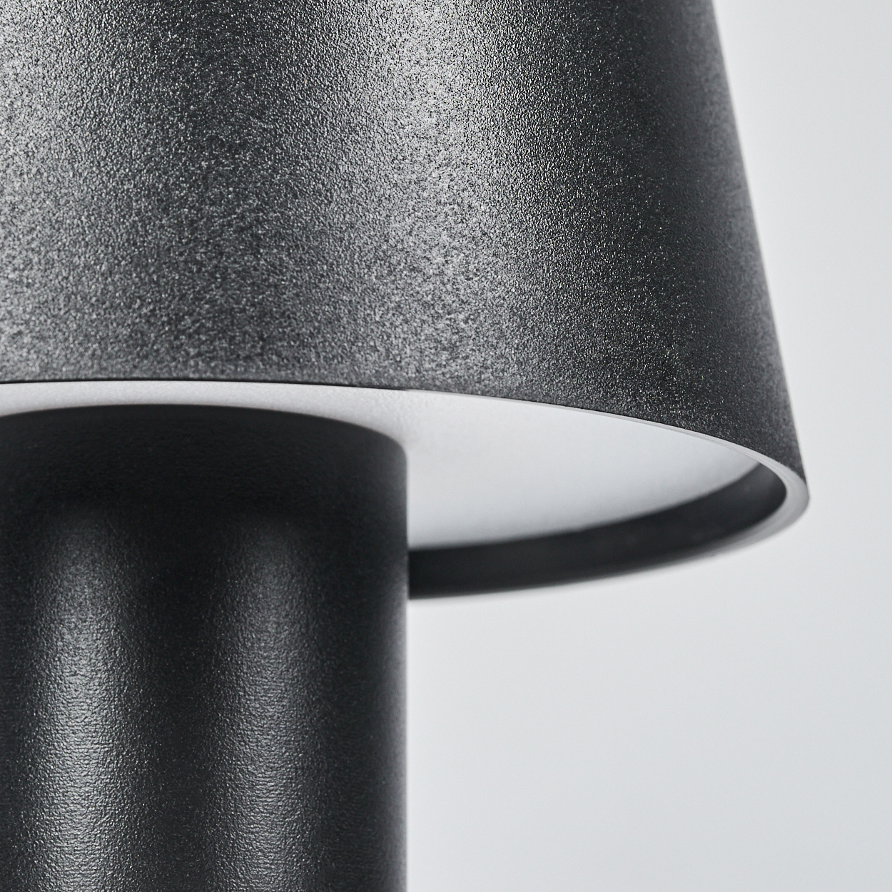 Nahaufnahme einer schwarzen Lampe mit Textur. Der Lampenschirm ist nach unten gerichtet.