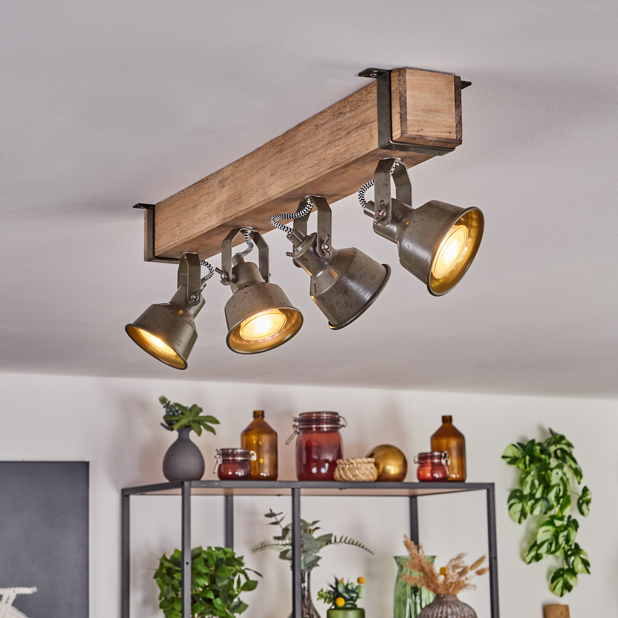 Deckenspot mit Holzträger und vier Metalllampenschirmen, beleuchtet.