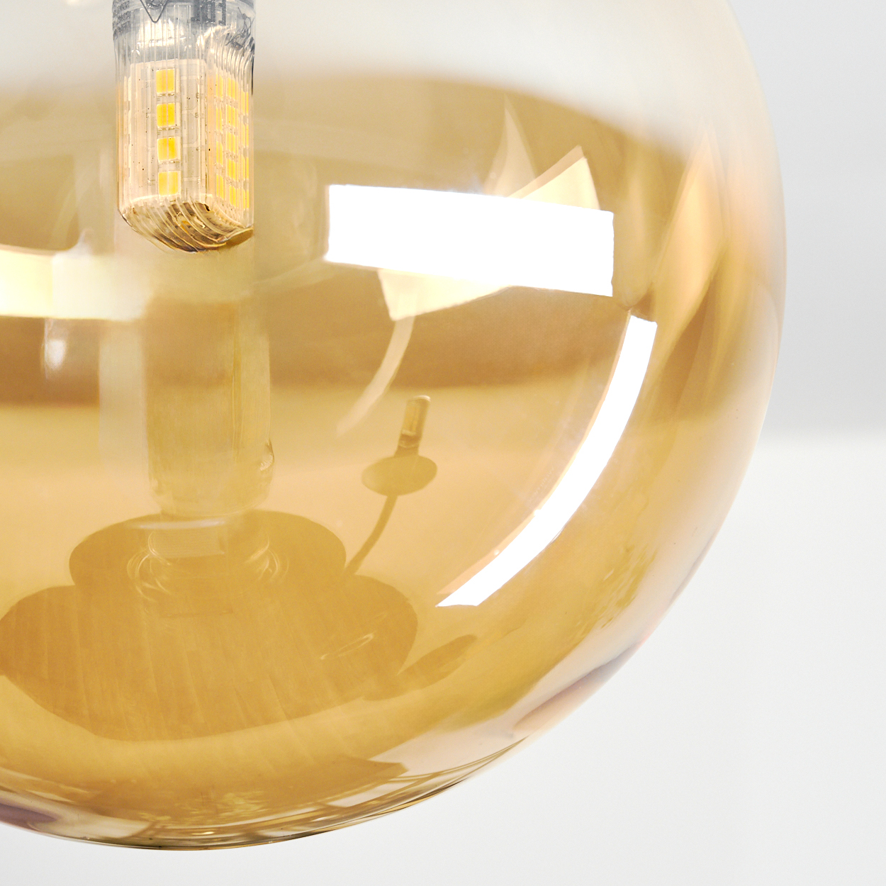 Eine bernsteinfarbene Glaskugel mit einer LED-Lampe und ihrem Sockel.