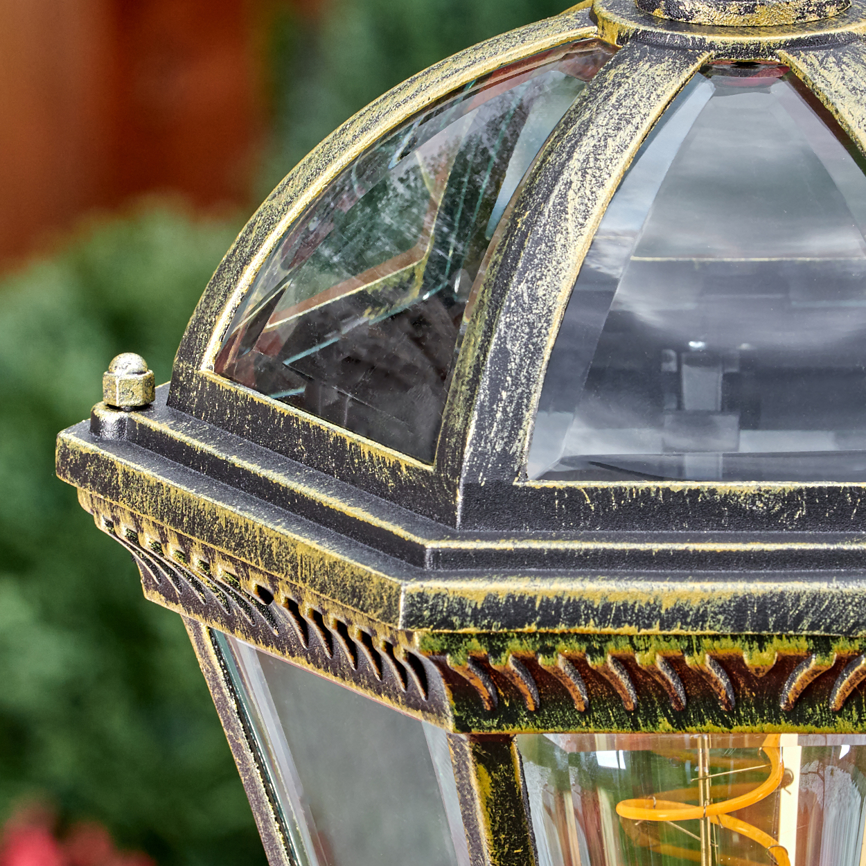 Detail einer alten schwarzen und goldenen Laterne mit Glasfenstern und sichtbarer Glühbirne.