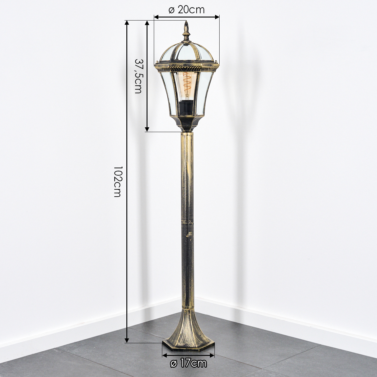 Eine hohe schwarze und goldene Stehlampe mit einem Glaslampenschirm und sichtbarer Glühbirne.